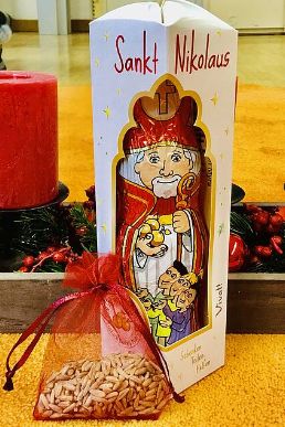 Man sieht einen Schokoladen-Nikolaus, vor dem ein kleines Chiffon-Säckchen mit Weizenkörnern liegt.